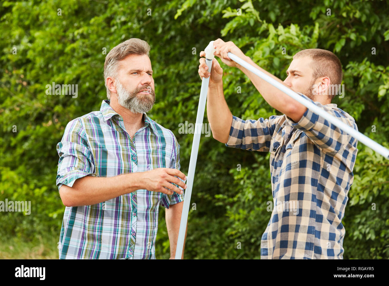 Two men build a tent or a stand together Stock Photo - Alamy