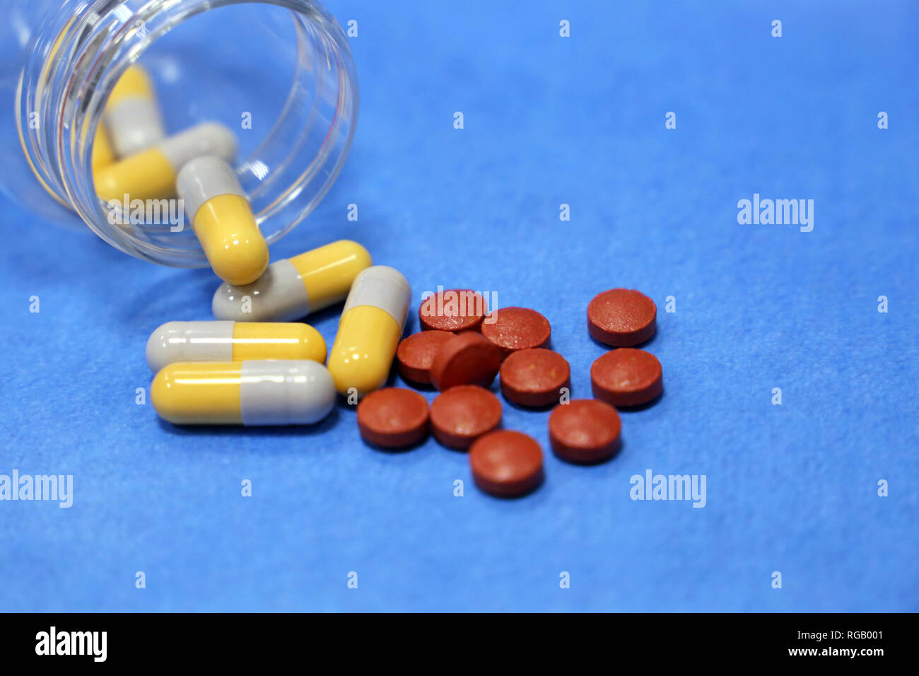 Pills and capsules in bottle on blue background. Concept of drugs, antibiotics, vitamins, pharmacy, treatment during the cold season, polypharmacy Stock Photo
