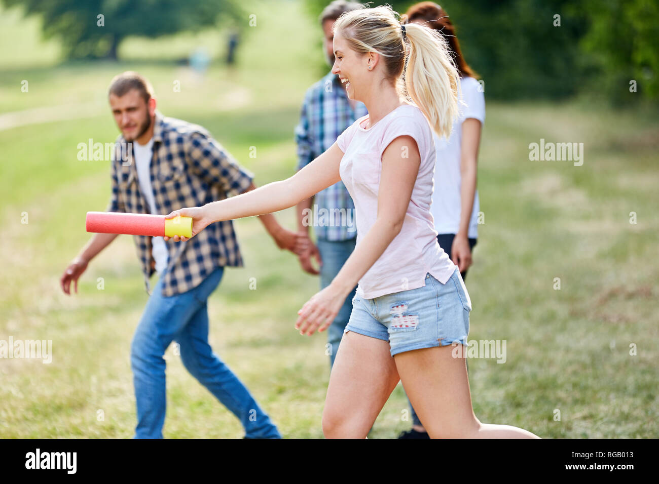 Young woman hands the baton in a relay race at the teambuilding workshop Stock Photo