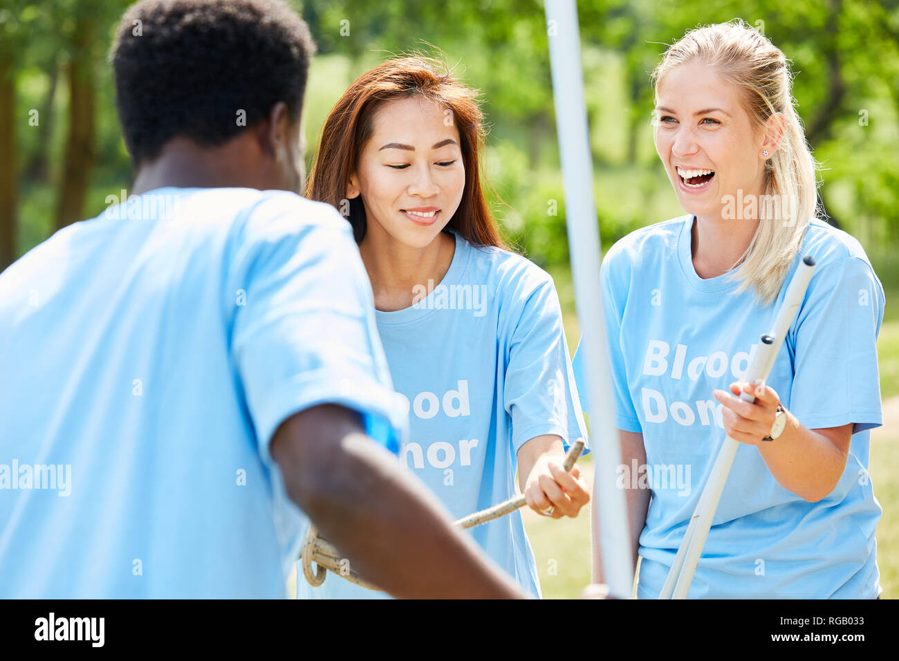 Three young people together build up an action stand for the blood donation service Stock Photo