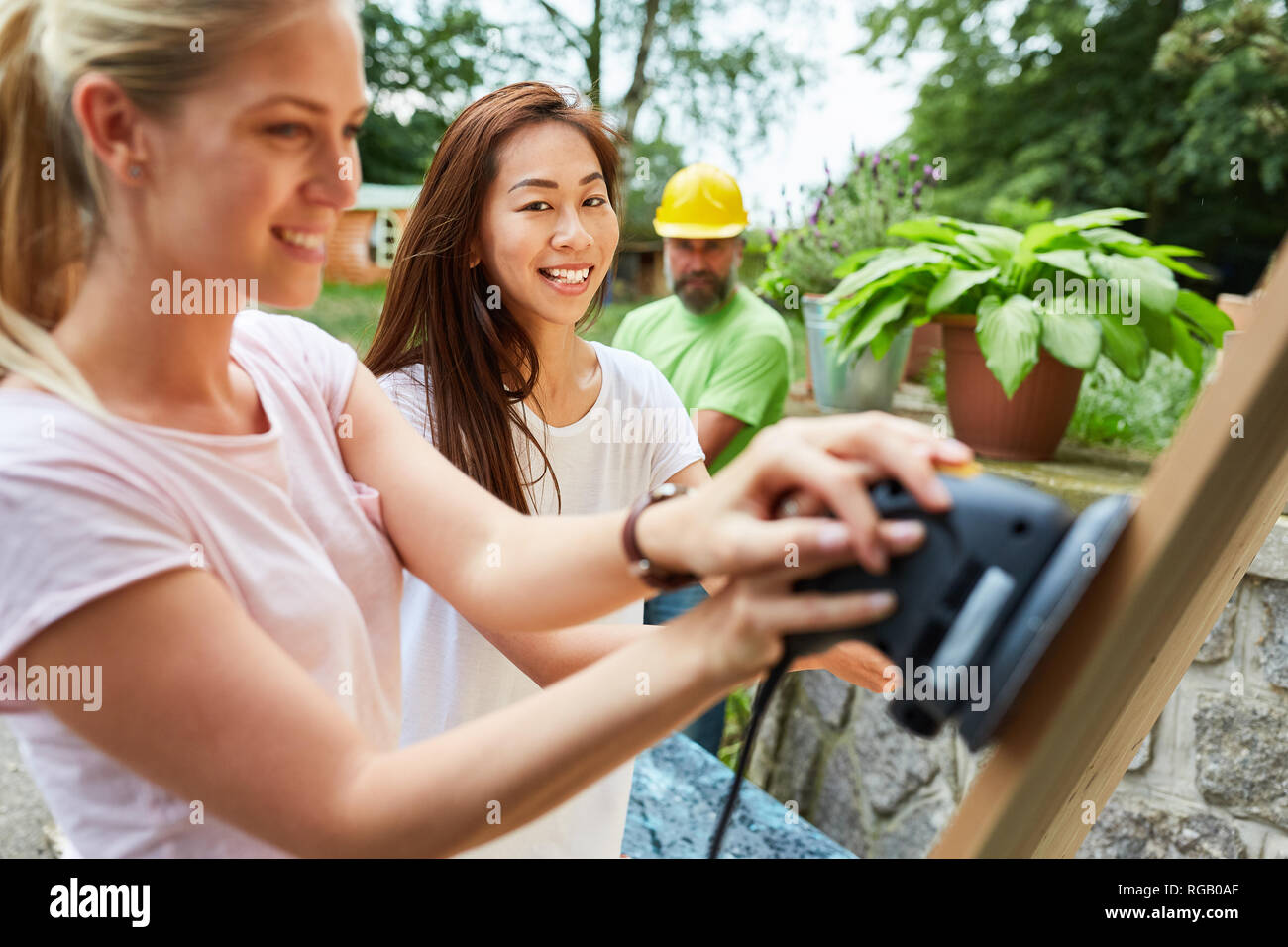 Two young women doing DIY grind wood with the grinder Stock Photo