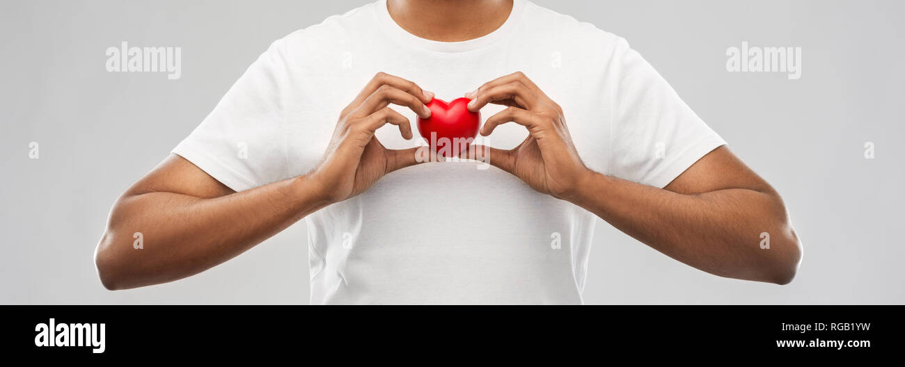 man holding red heart over grey background Stock Photo - Alamy