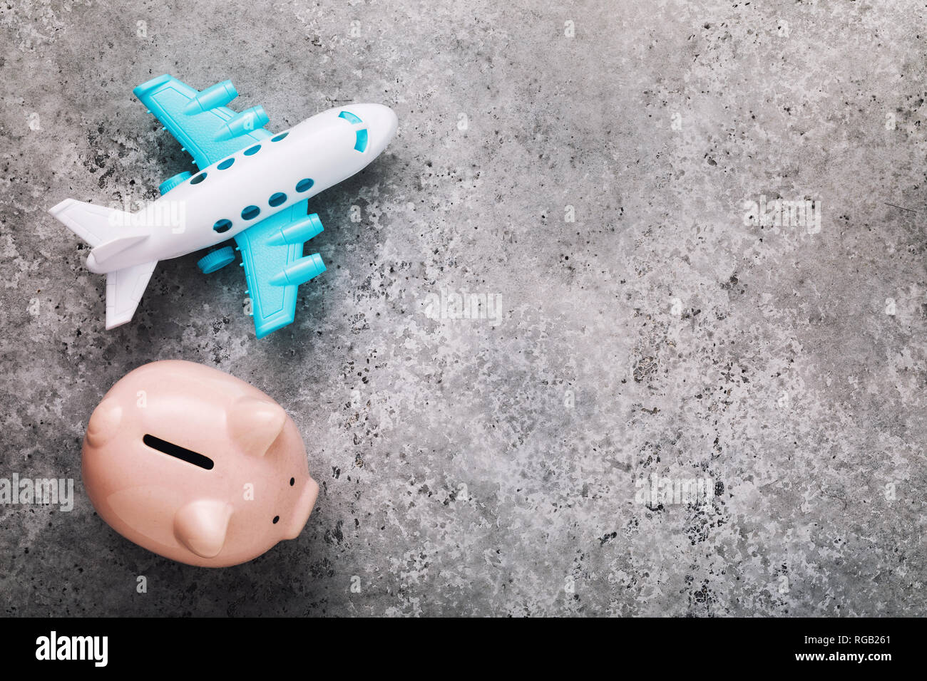 Concept of saving money for the flight. Piggy bank and plane on the table with copy space Stock Photo