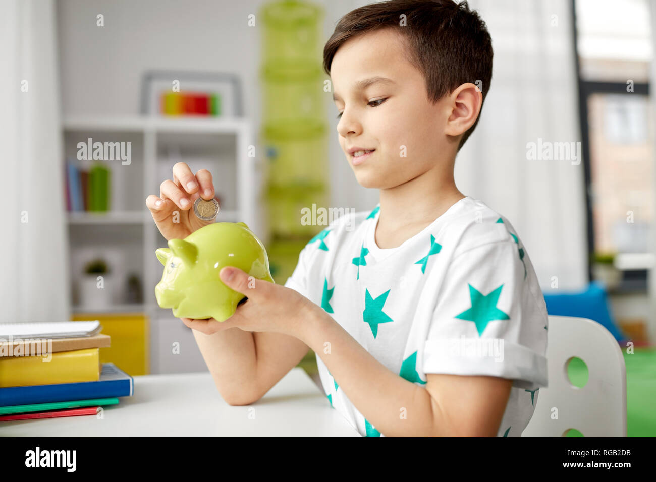 little boy putting coin into piggy bank at home Stock Photo - Alamy