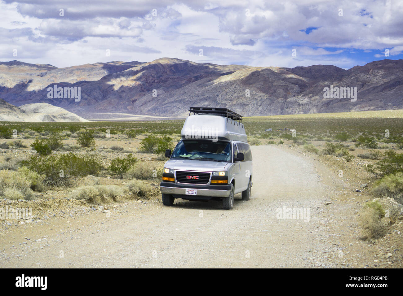 May 27, 2018 Death Valley / CA / USA - Modified GMC minivan travelling on an unpaved road through a remote area of Death Valley; converting standard v Stock Photo