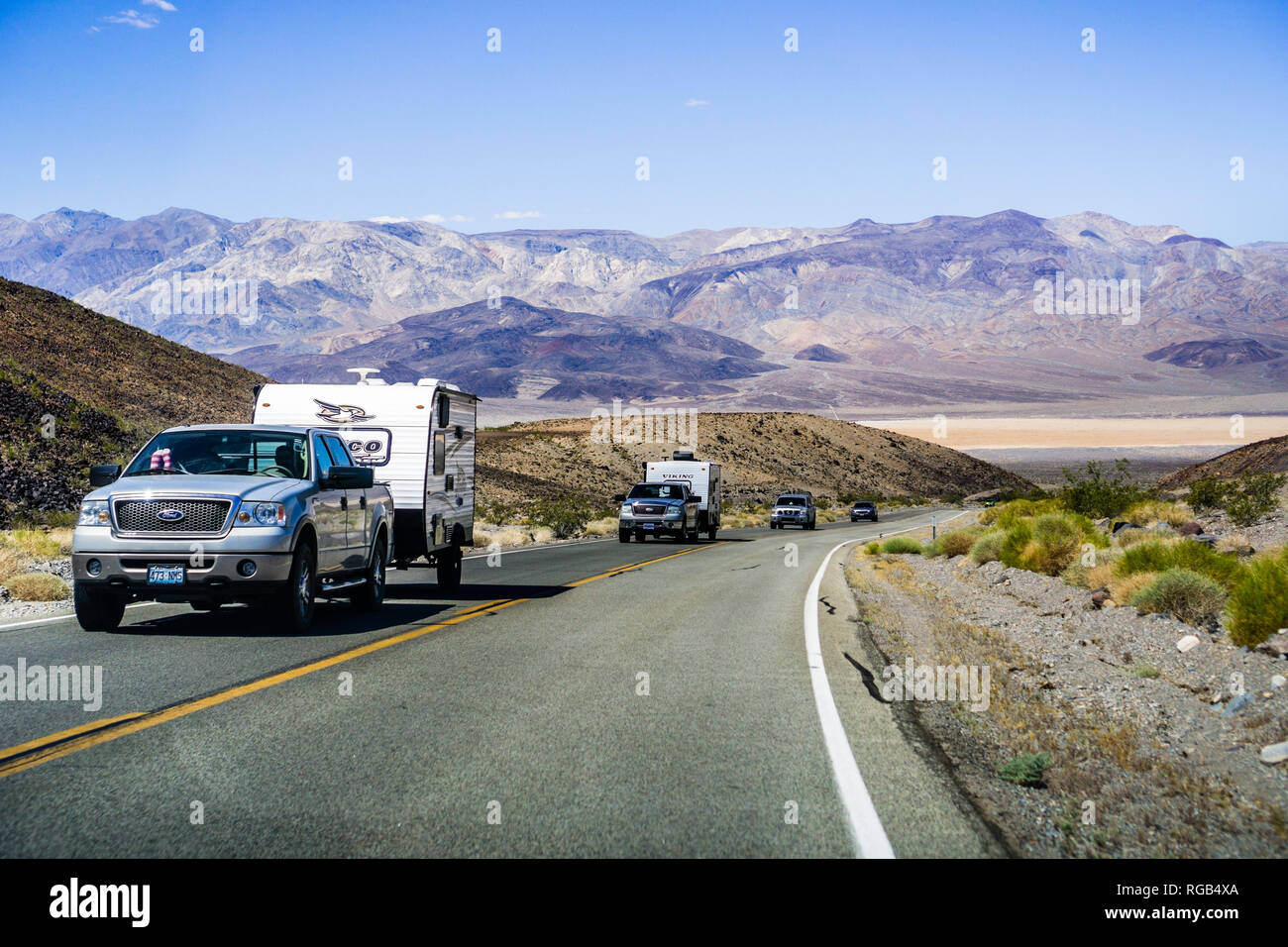 May 28, 2018 Death Valley / CA / USA - Pick up trucks with RV travel trailers driving though Death Valley National Park; Panamint Valley visible in th Stock Photo
