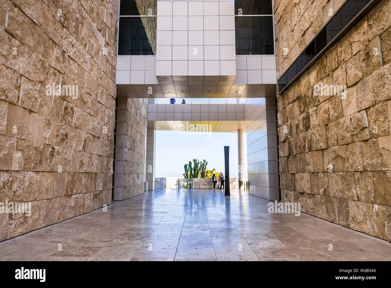June 8, 2018 Los Angeles / CA / USA - Walking corridor between travertine covered walls and below an aerial walkway connecting buildings at the Getty  Stock Photo