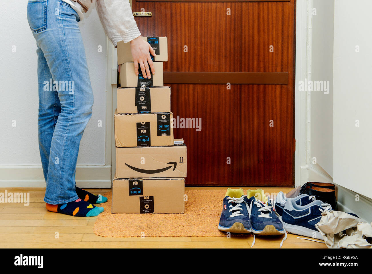 PARIS, FRANCE - JAN 13, 2018: Preparing for Prime Day Amazon Prime packages delivered to a home door woman trying to lift heavy boxes. Stock Photo