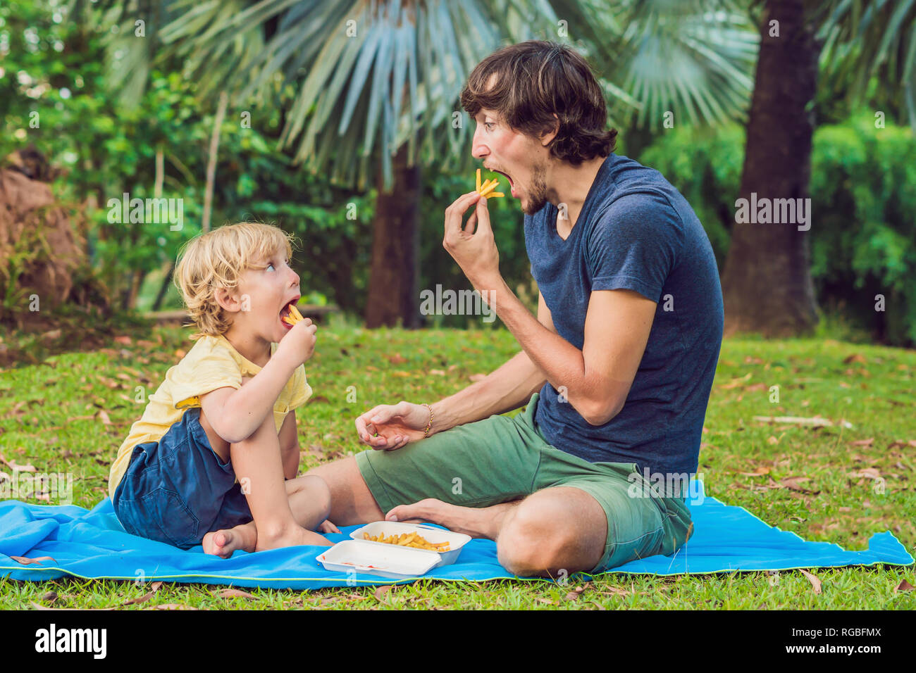 Cute healthy preschool kid boy eats french fries potatoes with ketchup with his father. child