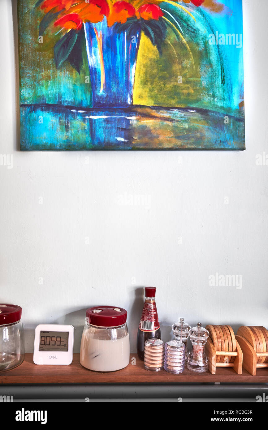Colorful, bright painting above various kitchen and table accessories