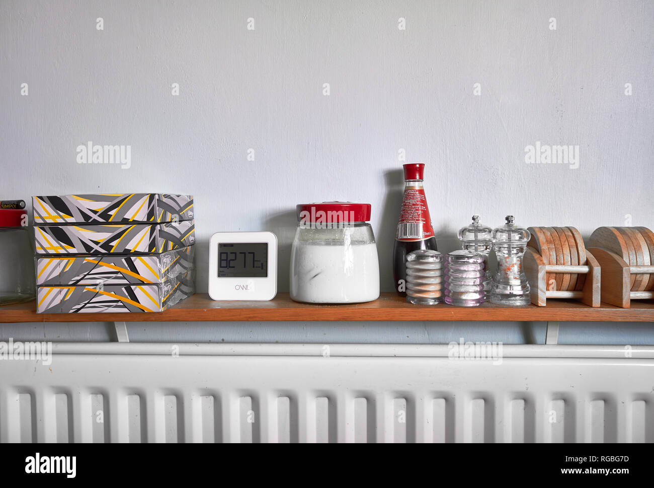 various kitchen and table accessories on a shelf over a radiator Stock