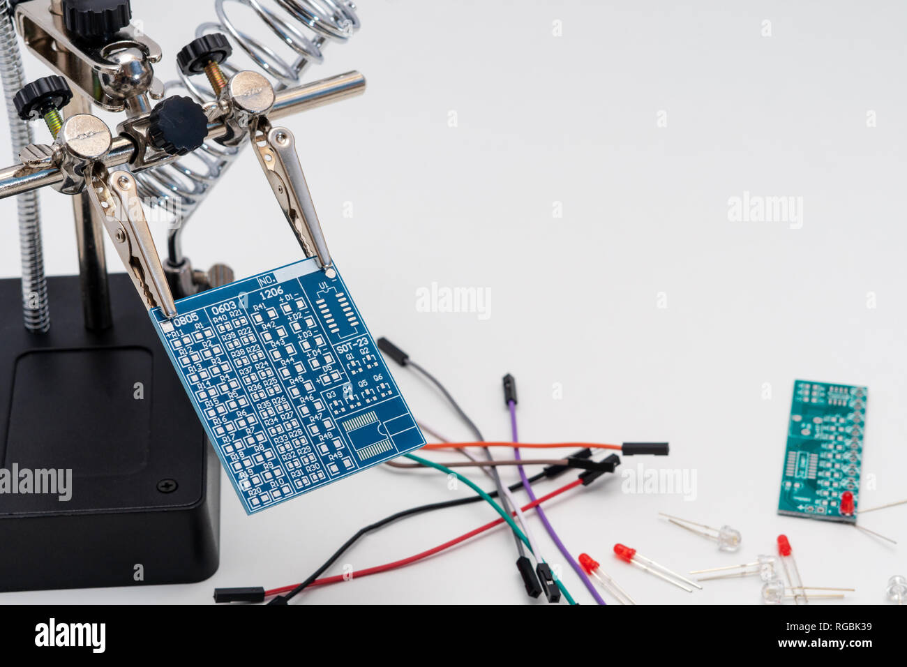 Blue circuit board in soldering helping hands (third hand or auxiliary
