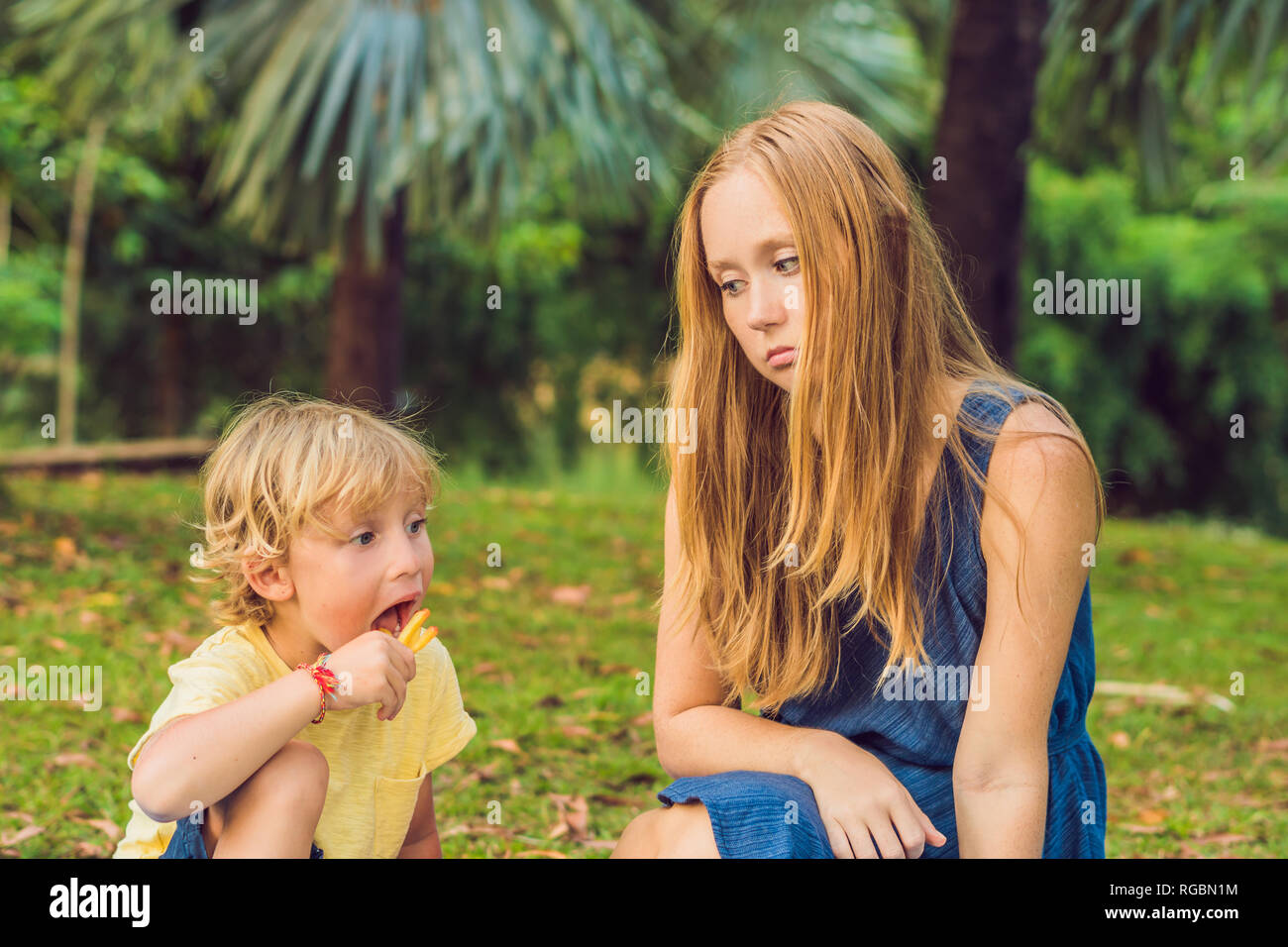 Cute healthy preschool kid boy eats french fries potatoes with ketchup with his mom. child