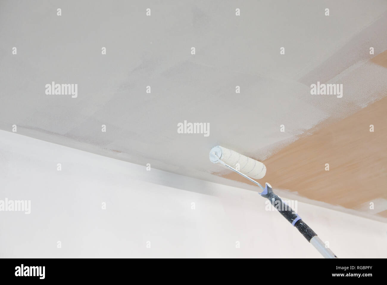 A Paint Roller Applies White Emulsion To A Bare Plaster