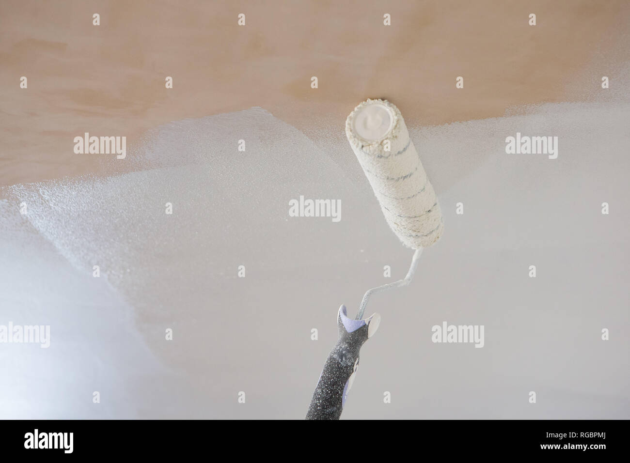A Paint Roller Applies White Emulsion To A Bare Plaster