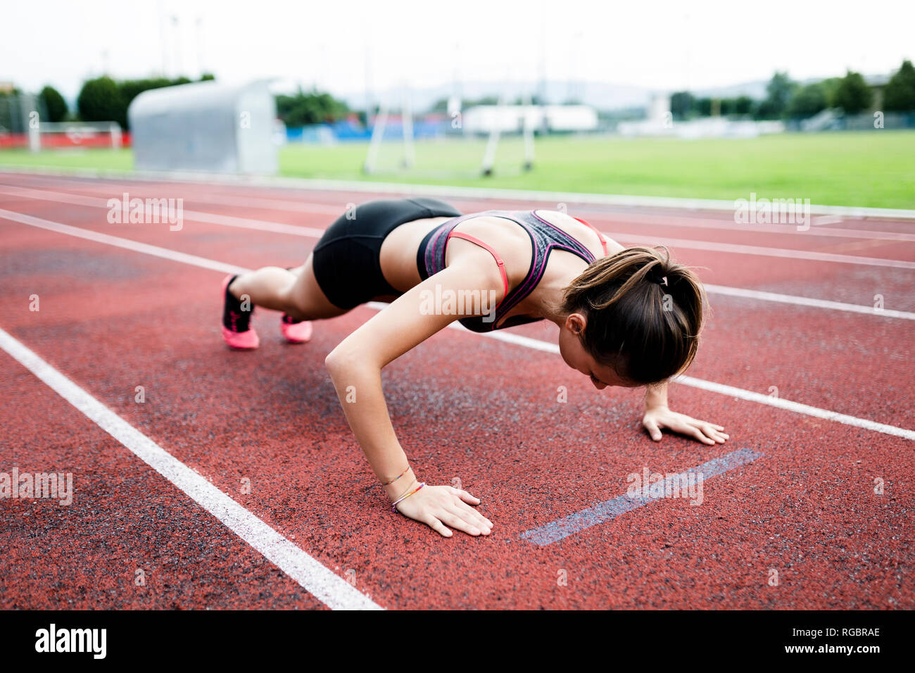 Teenage runner doing push ups on race track Stock Photo