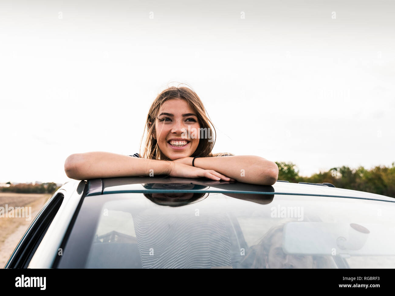 Smiling young woman looking out of sunroof of a car Stock Photo Alamy