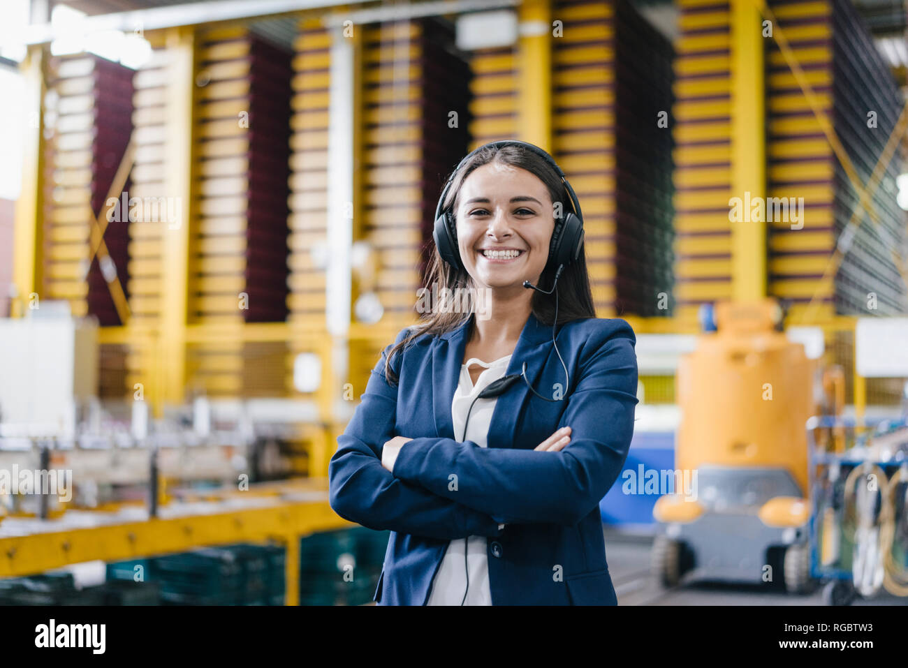 Confident woman standing in logistics center, with arms crossed Stock Photo