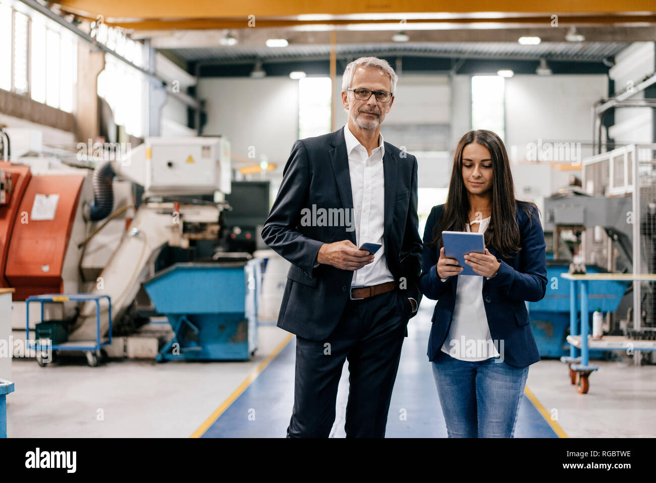 Businessman an woman in high tech enterprise, having a meeting in factory workshop Stock Photo