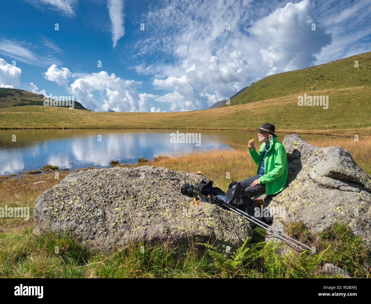 Italy, Lombardy, hiker sitting at lake and eating an apple Stock Photo