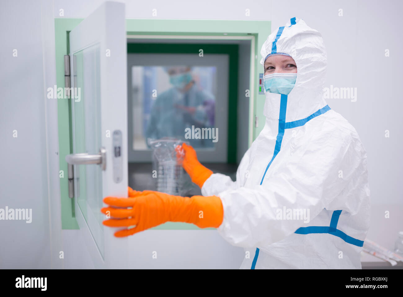 Lab technician wearing cleanroom overall at material sluice Stock Photo