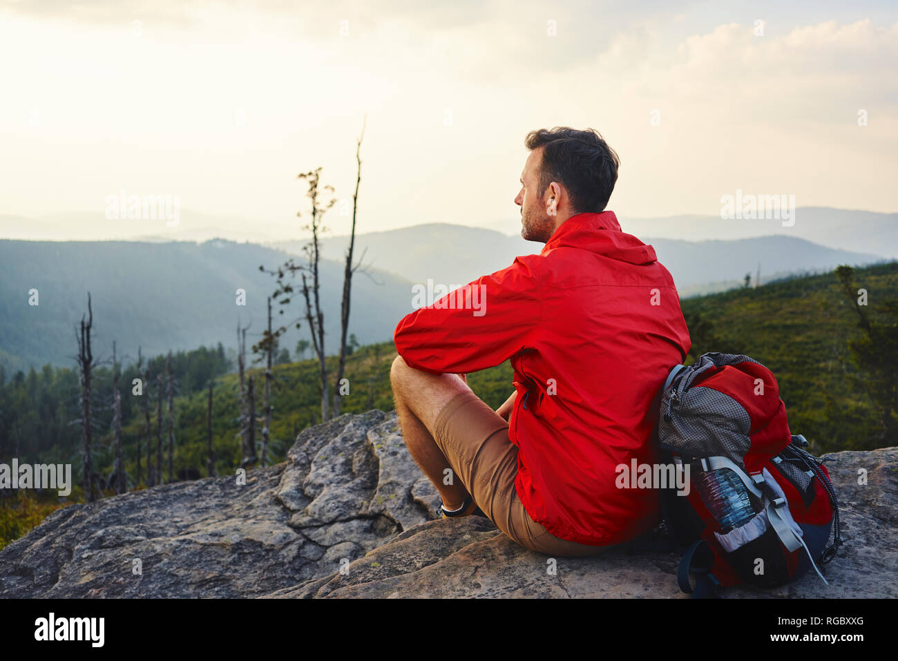Man sitting on rock enjoying the view during hiking trip Stock Photo