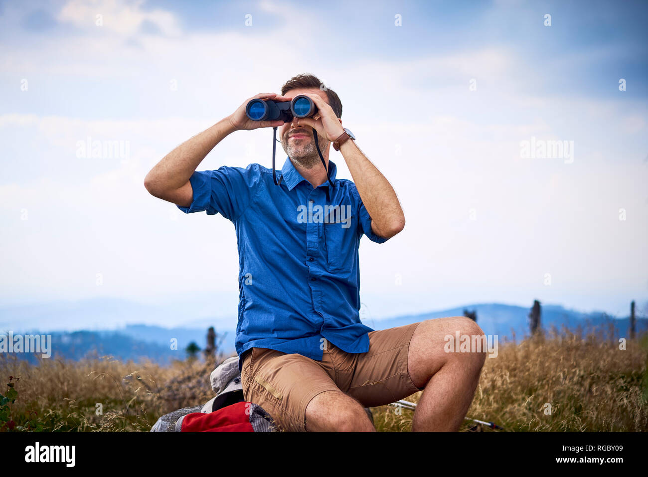 Man looking through binoculars during hiking trip Stock Photo