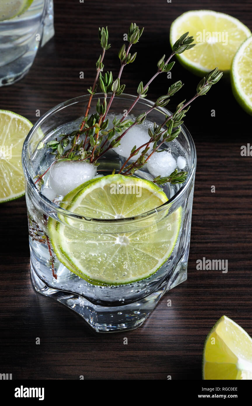 Cocktail with white rum and tonic, a slice of lime and thyme Stock Photo Alamy