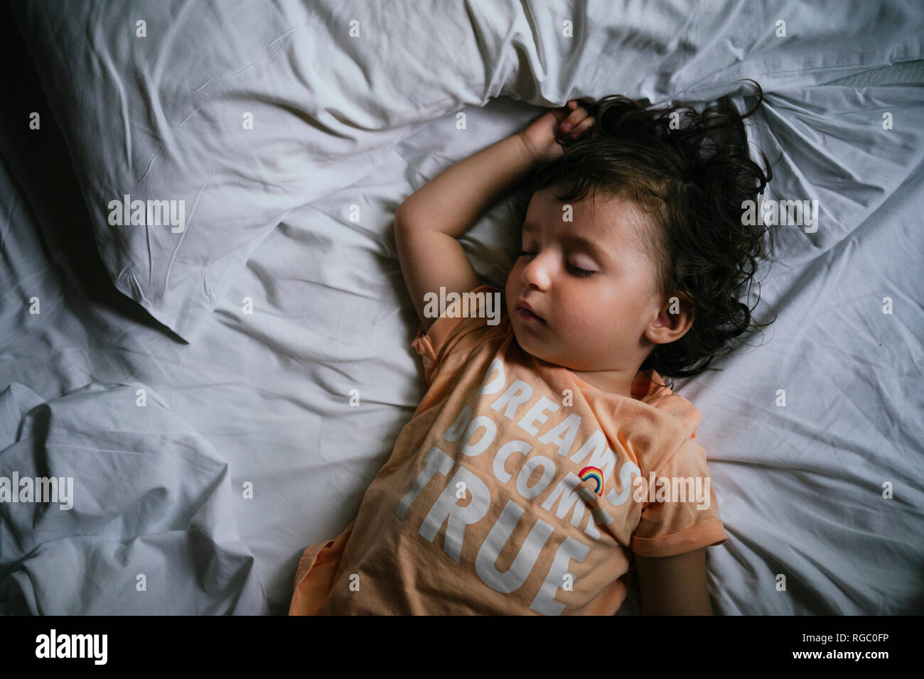 Baby girl sleeping on bed with tshirt message 'Dreams do come true