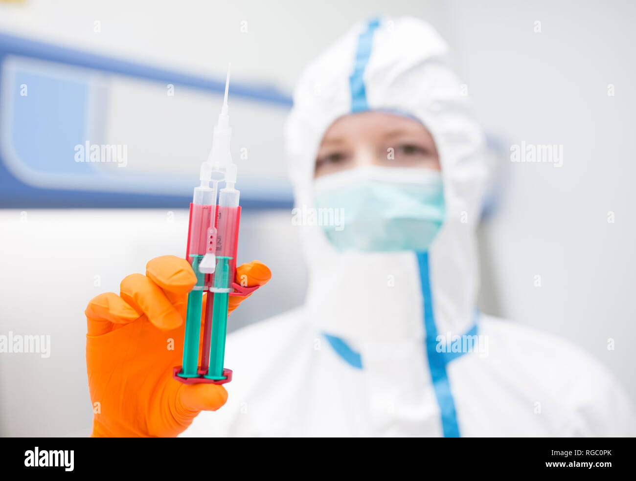 Lab technician wearing cleanroom overall holding syringe Stock Photo