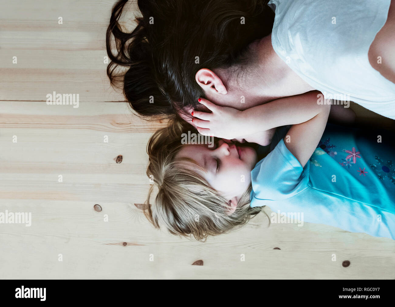 Daughter caressing mother, lying on floor Stock Photo