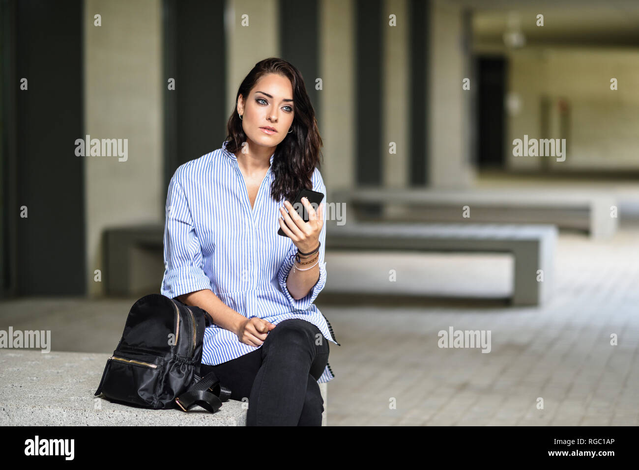 Portrait of pensive student with smartphone on campus Stock Photo