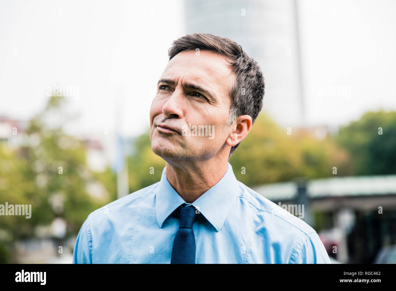 Portrait of businessman in city park thinking Stock Photo