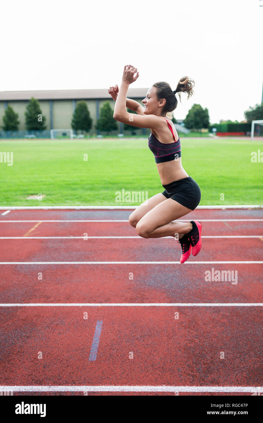 Teenage runner, jumping for joy on race track Stock Photo