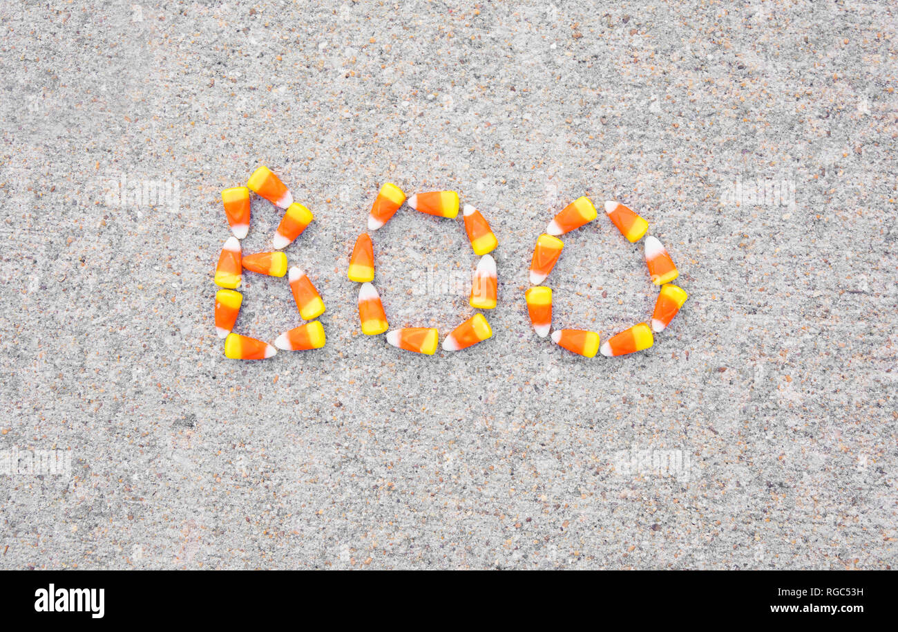 The word Boo spelled out in candy corn on a sidewalk.  The word is centered in the photo. Stock Photo