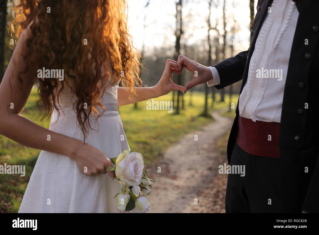 Newly wed bridal couple touching hands, making heart shaped finger frame Stock Photo