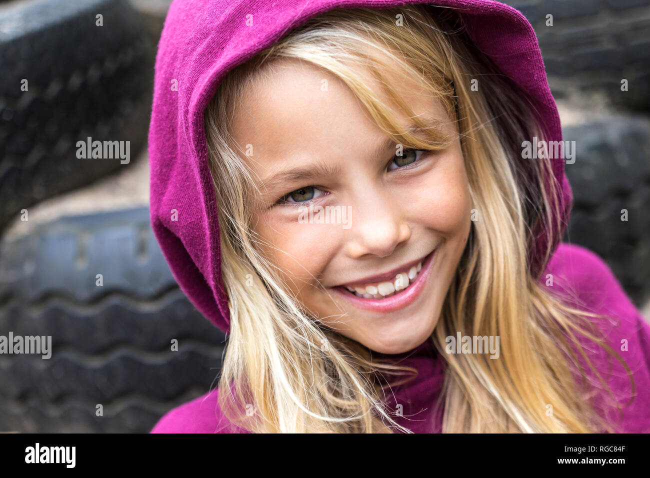 Portrait of smiling blond girl wearing pink hooded jacket Stock Photo