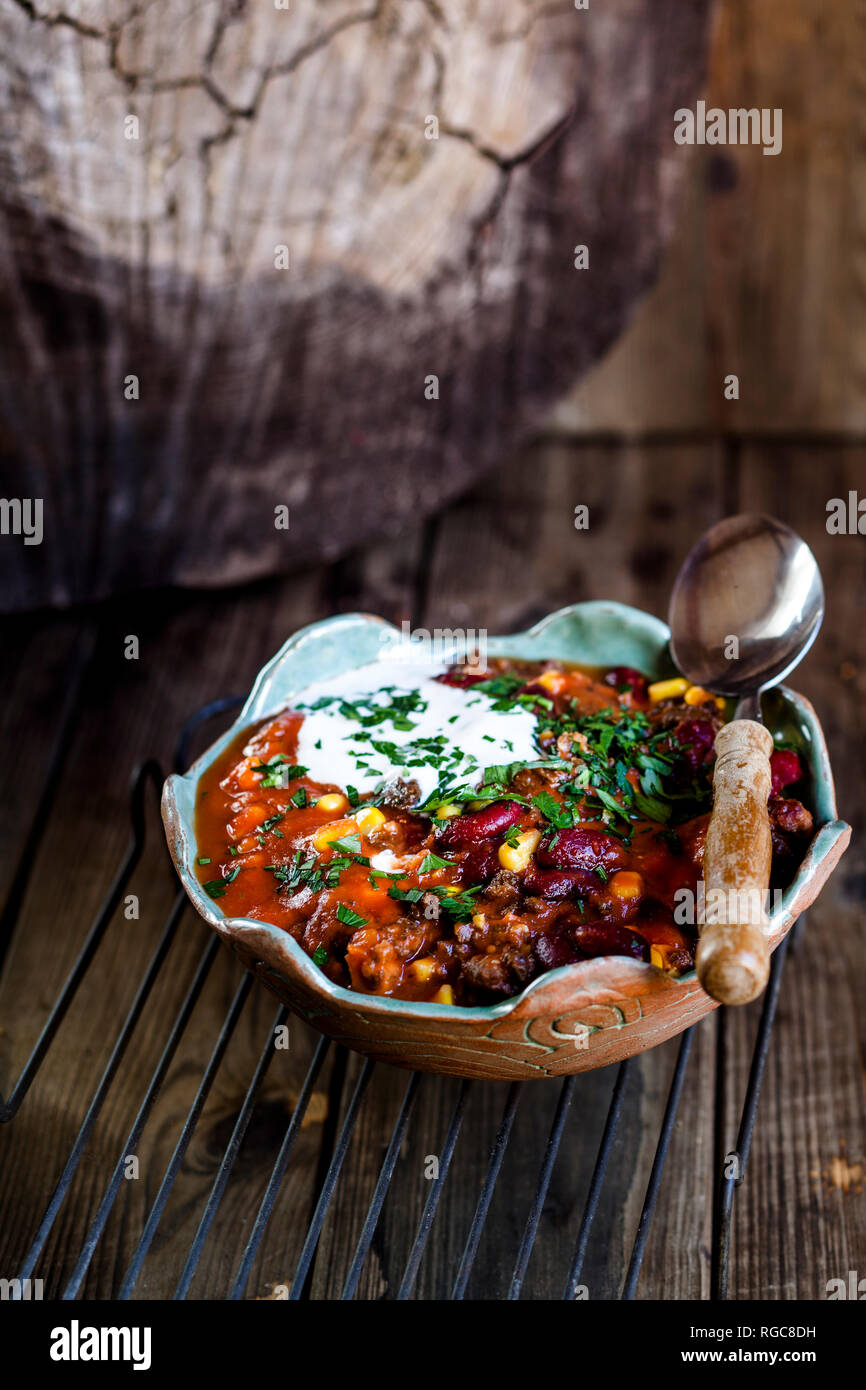 Chili con carne with kidney beans and corn, sour cream, parsley Stock Photo