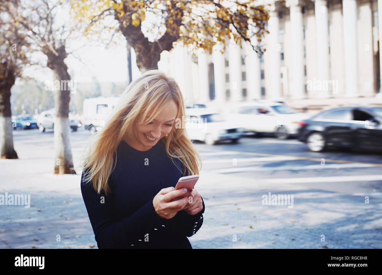 Smiling blond woman using smartphone in the city Stock Photo