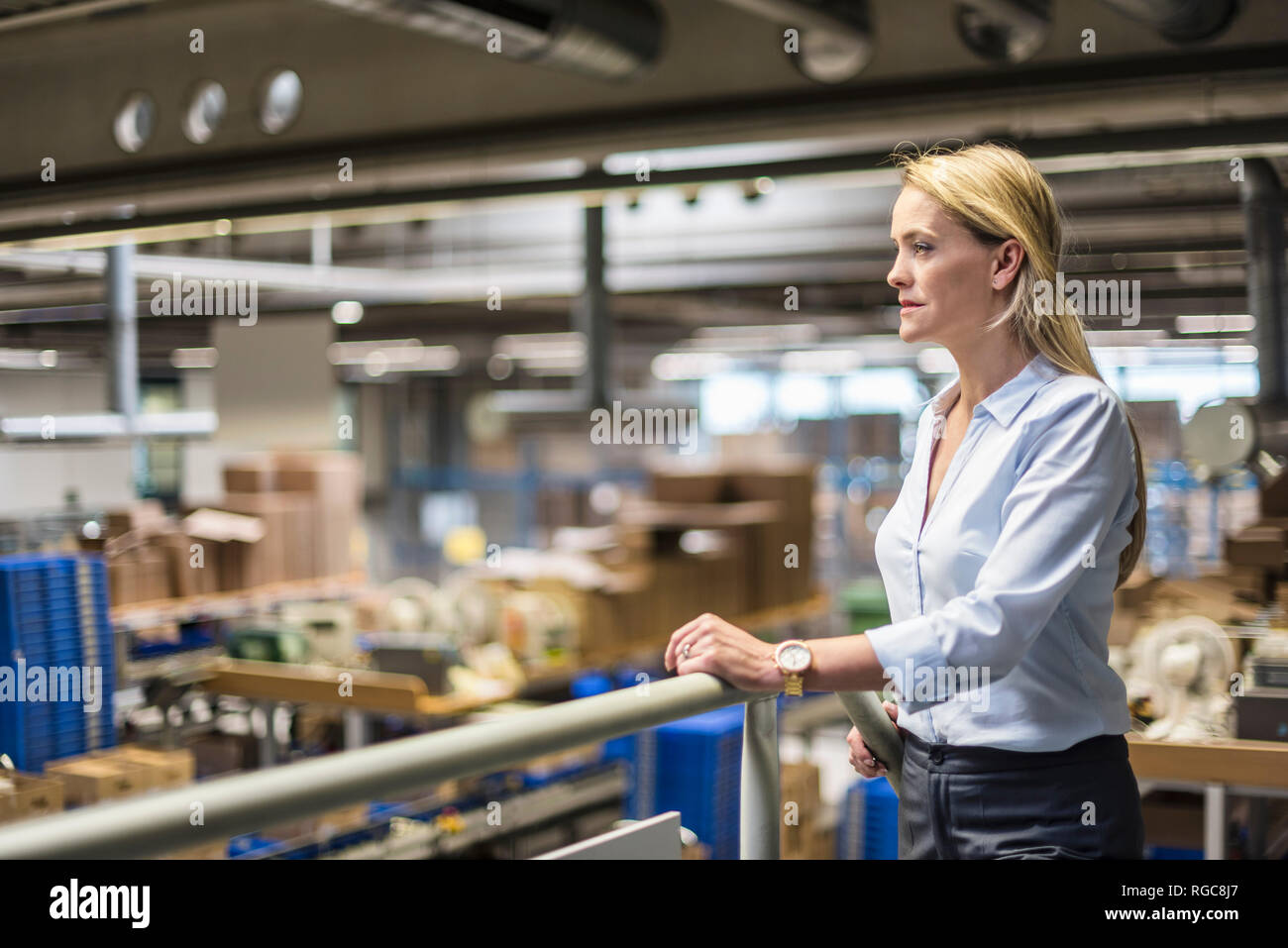 Businesswoman in factory overlooking storehouse Stock Photo