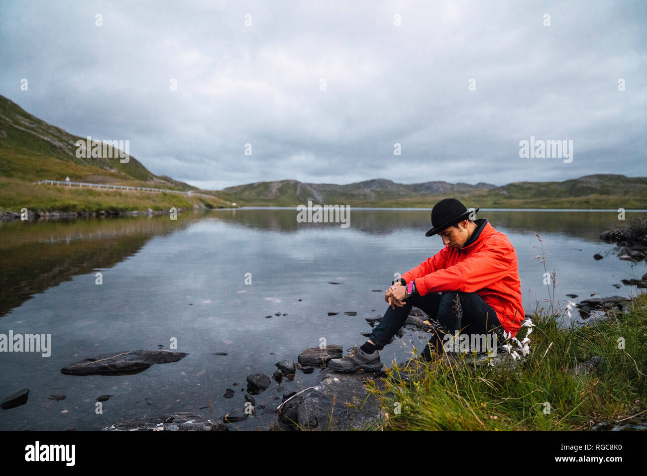 Young man sitting sad at a lake Stock Photo