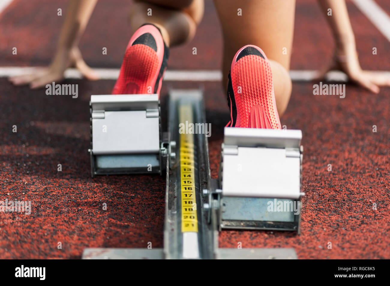 Teenage runner kneeling on starting block, close up Stock Photo