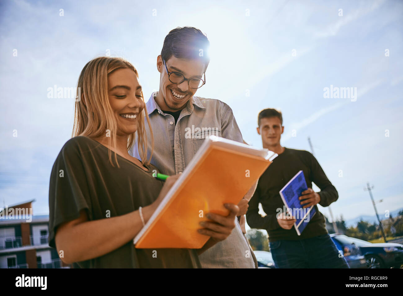 Happy students standing outdoors sharing documents Stock Photo