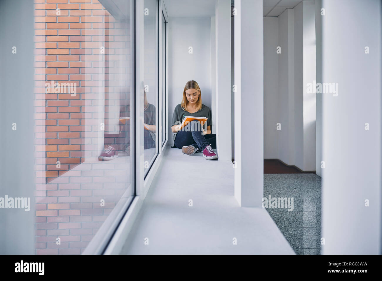 Student sitting at the window in hallway learning Stock Photo