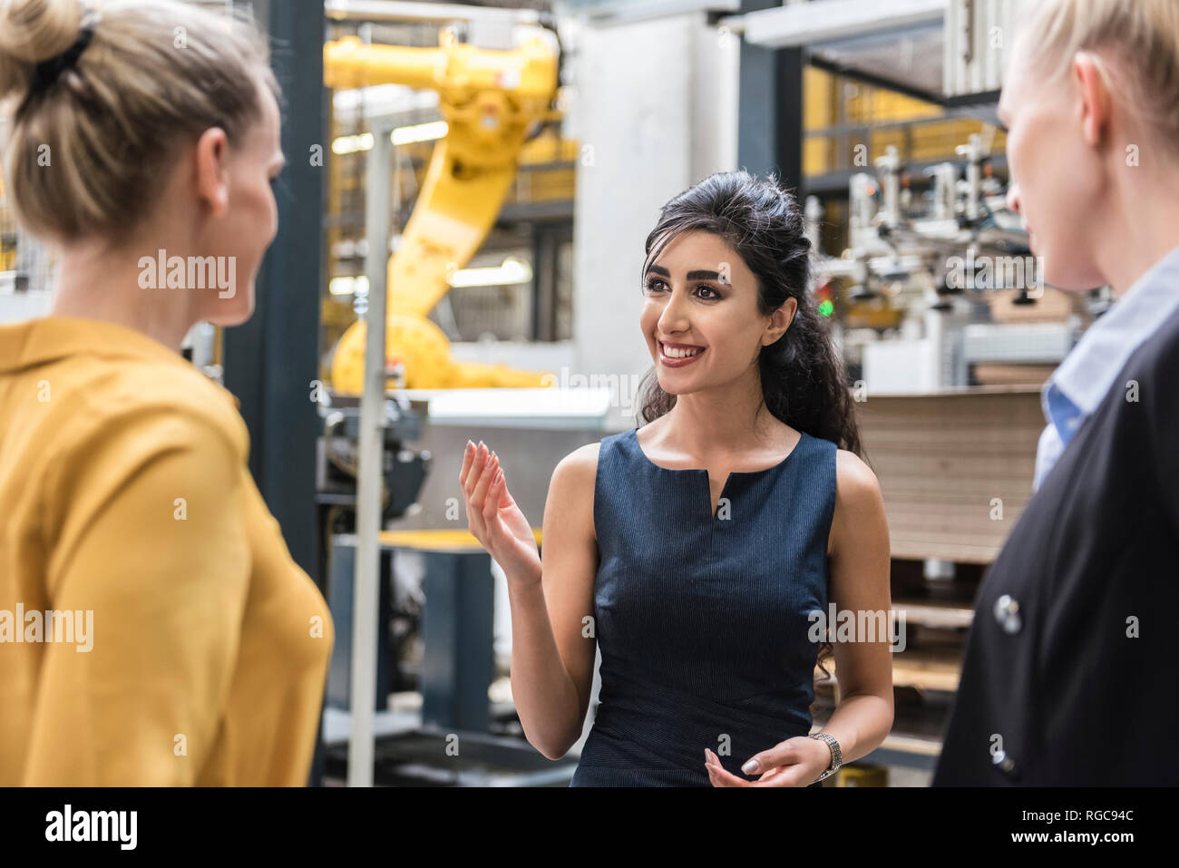 Portrait of smiling woman talking to colleagues in modern factory Stock Photo