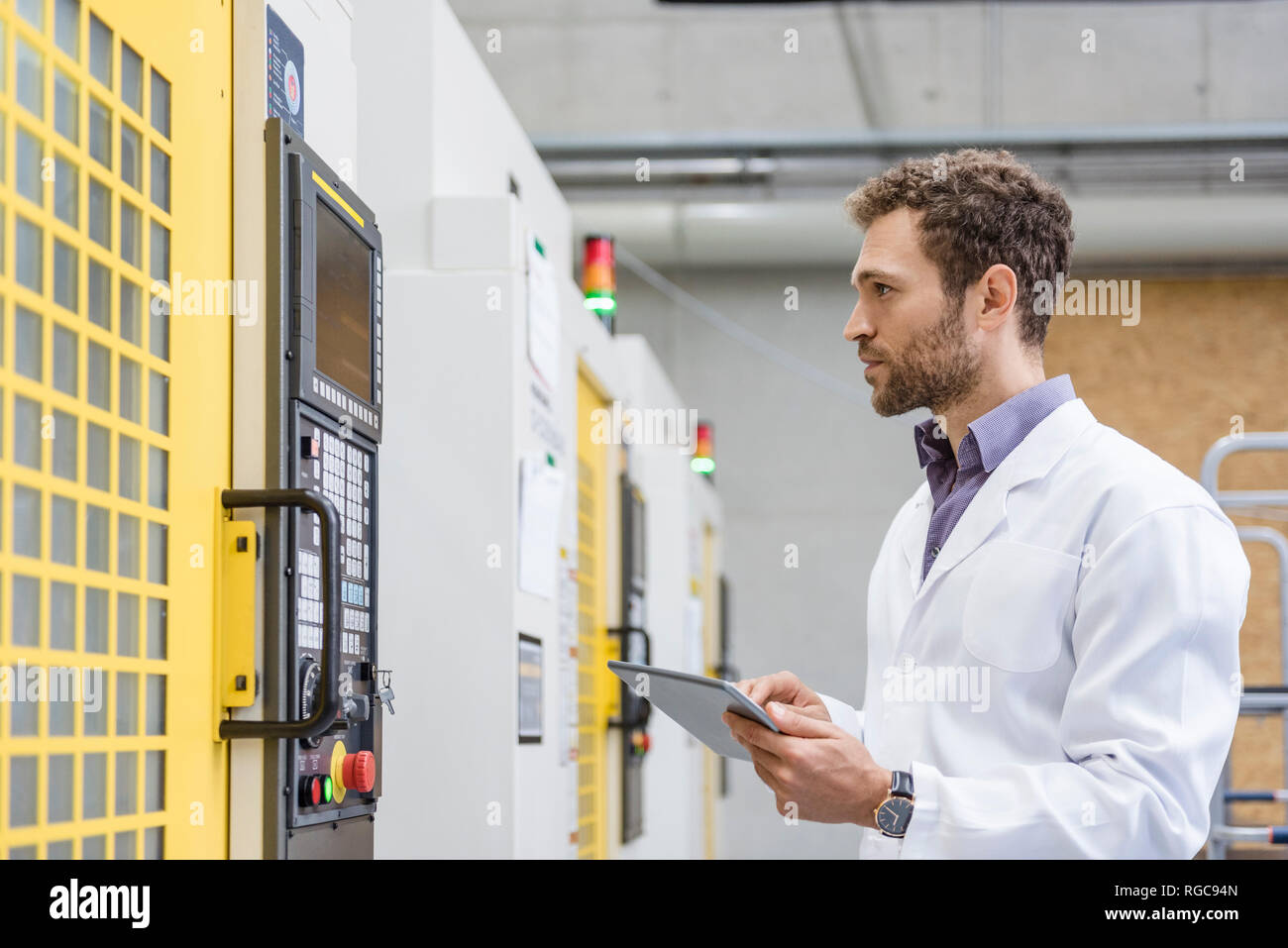 Employee checking manufacturing machines in high tech company, using