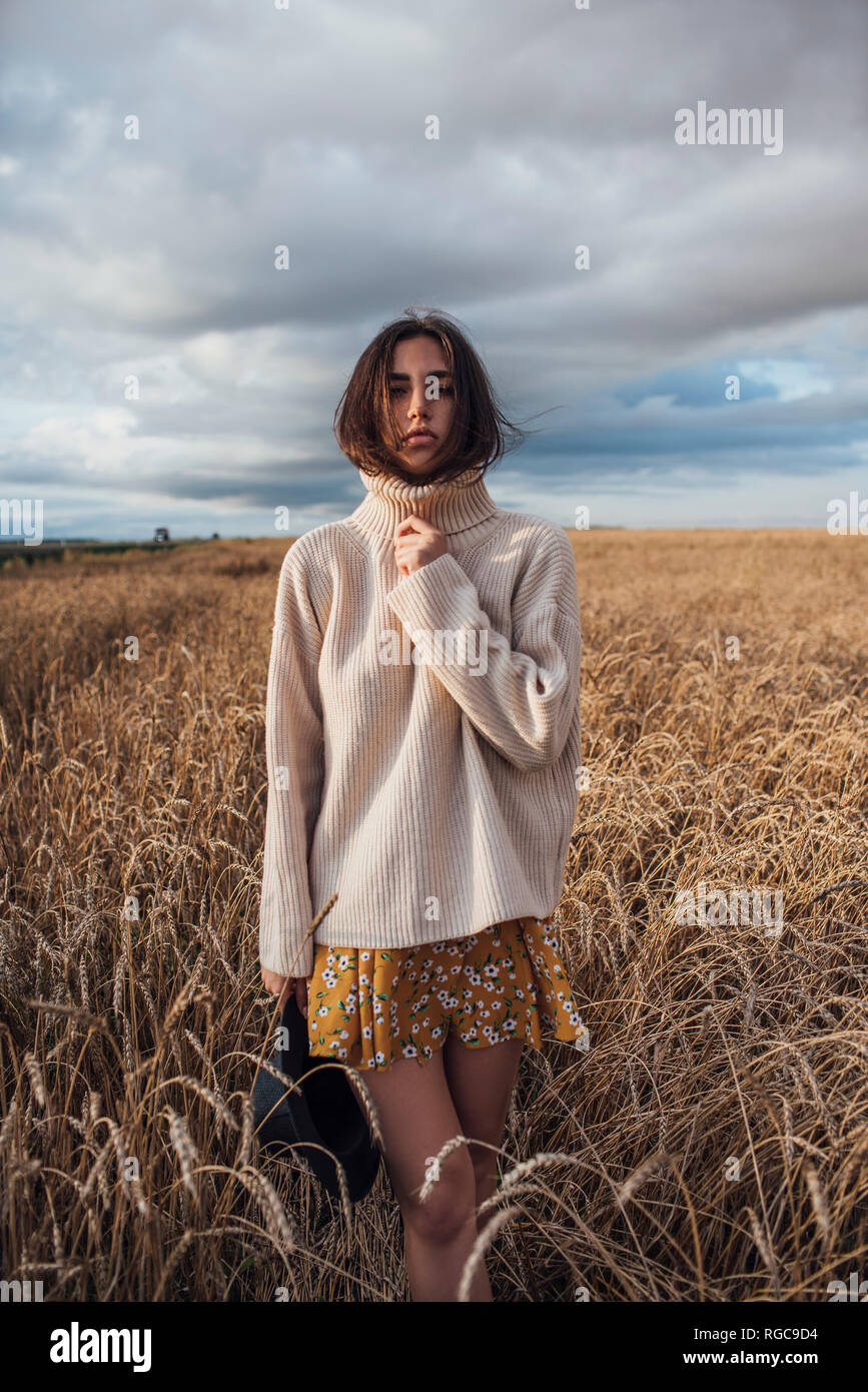 Portrait of young woman wearing oversized turtleneck pullover standing in corn field Stock Photo