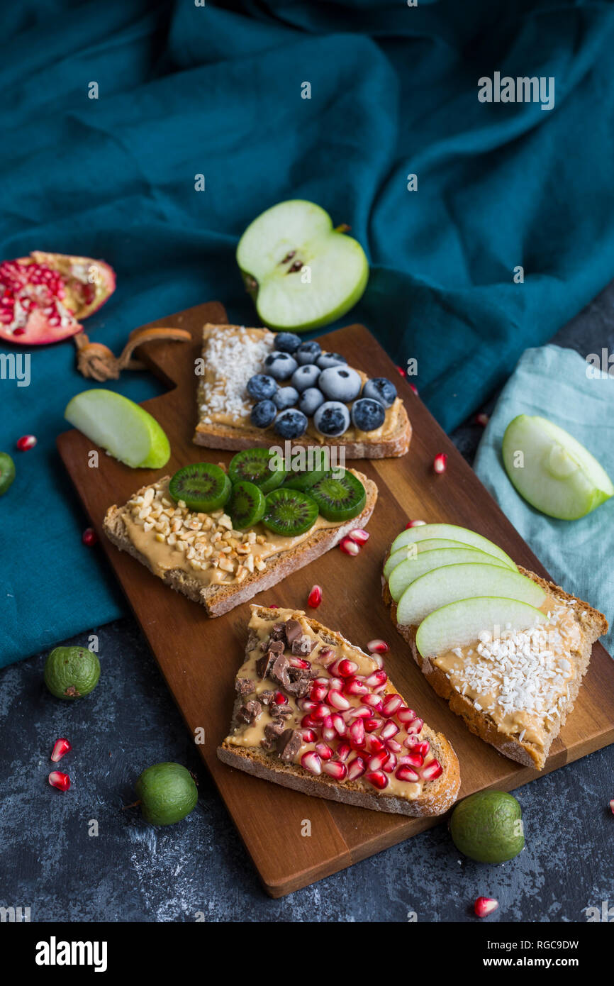Bread slices with various toppings on wooden board Stock Photo