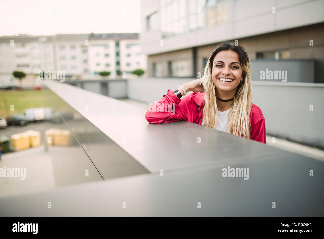 Portrait of a cheerful young woman leaning on a parapet Stock Photo