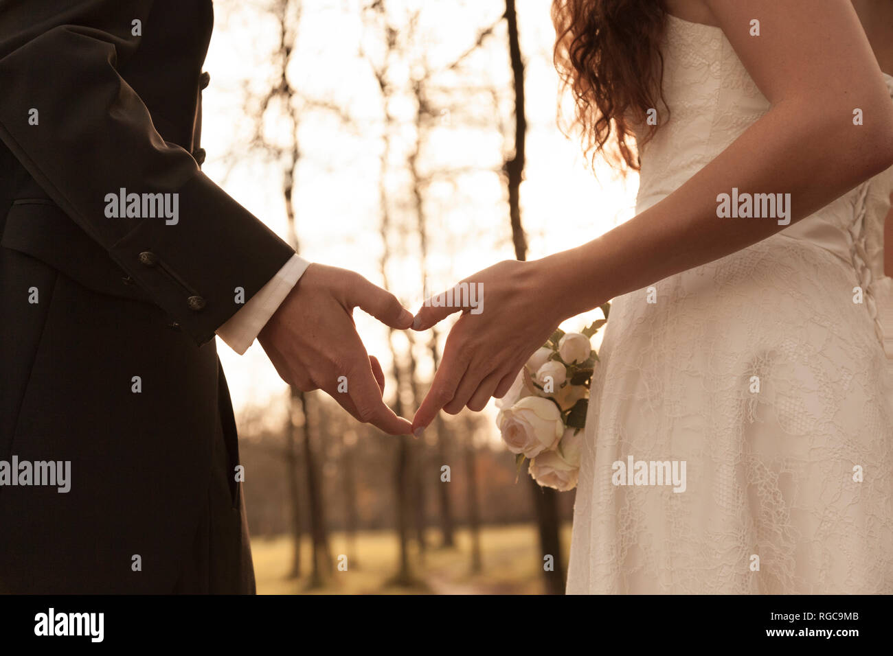 Newly wed bridal couple touching hands, making heart shaped finger frame Stock Photo